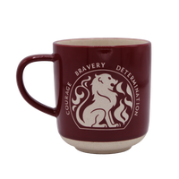 A burgundy stoneware mug with white text and a lion design, representing the Gryffindor house from the Harry Potter series.